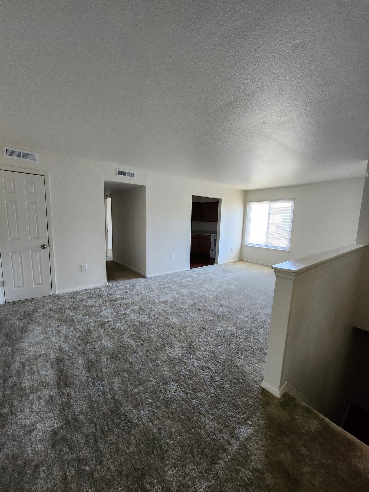 A bright living room at Prince Frederick Village with a blind-covered window, a closet, and a stairway beside a half wall